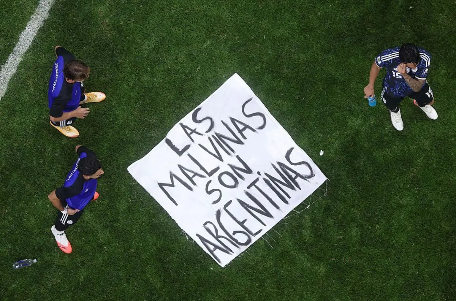 Getty Images A banner saying "Las Malvinas Son Argentinas" is on the ground of a pitch with three players standing around it